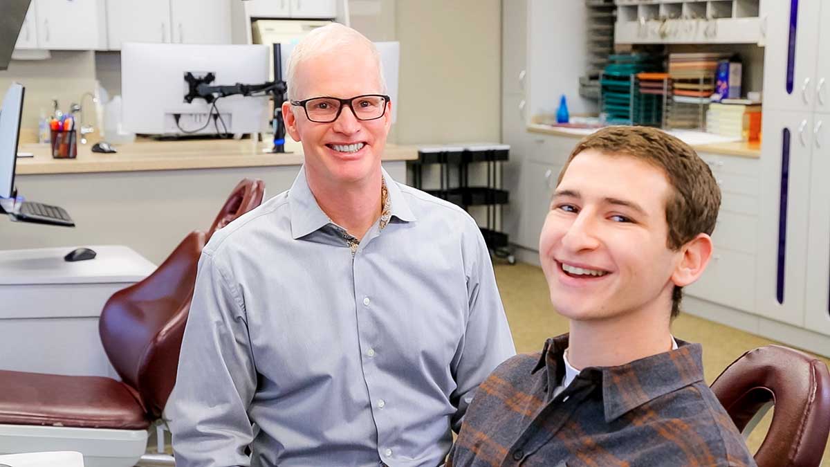 Two men smiling with braces.