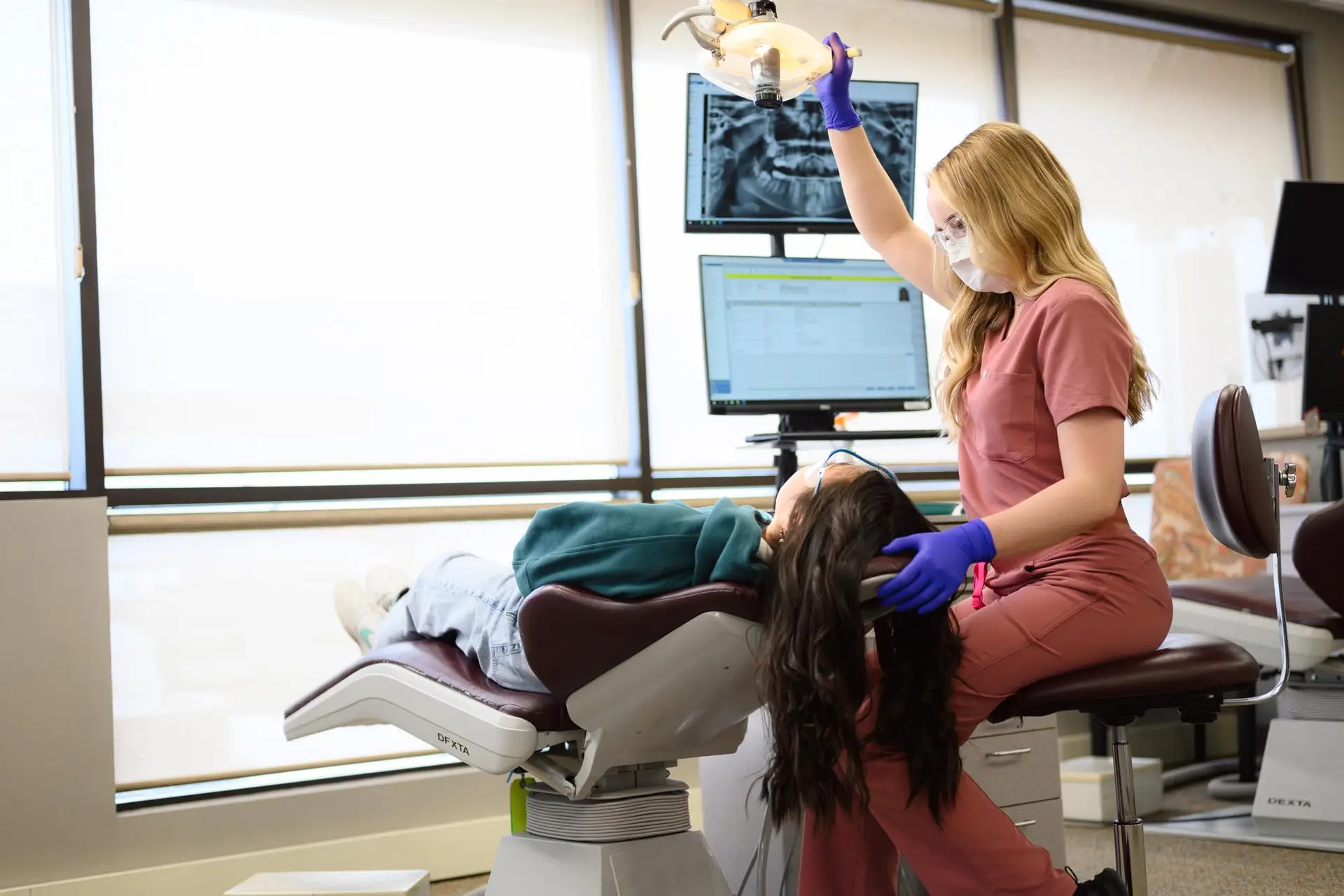 A woman, with Invisalign Teen aligners, sitting in a dental chair.