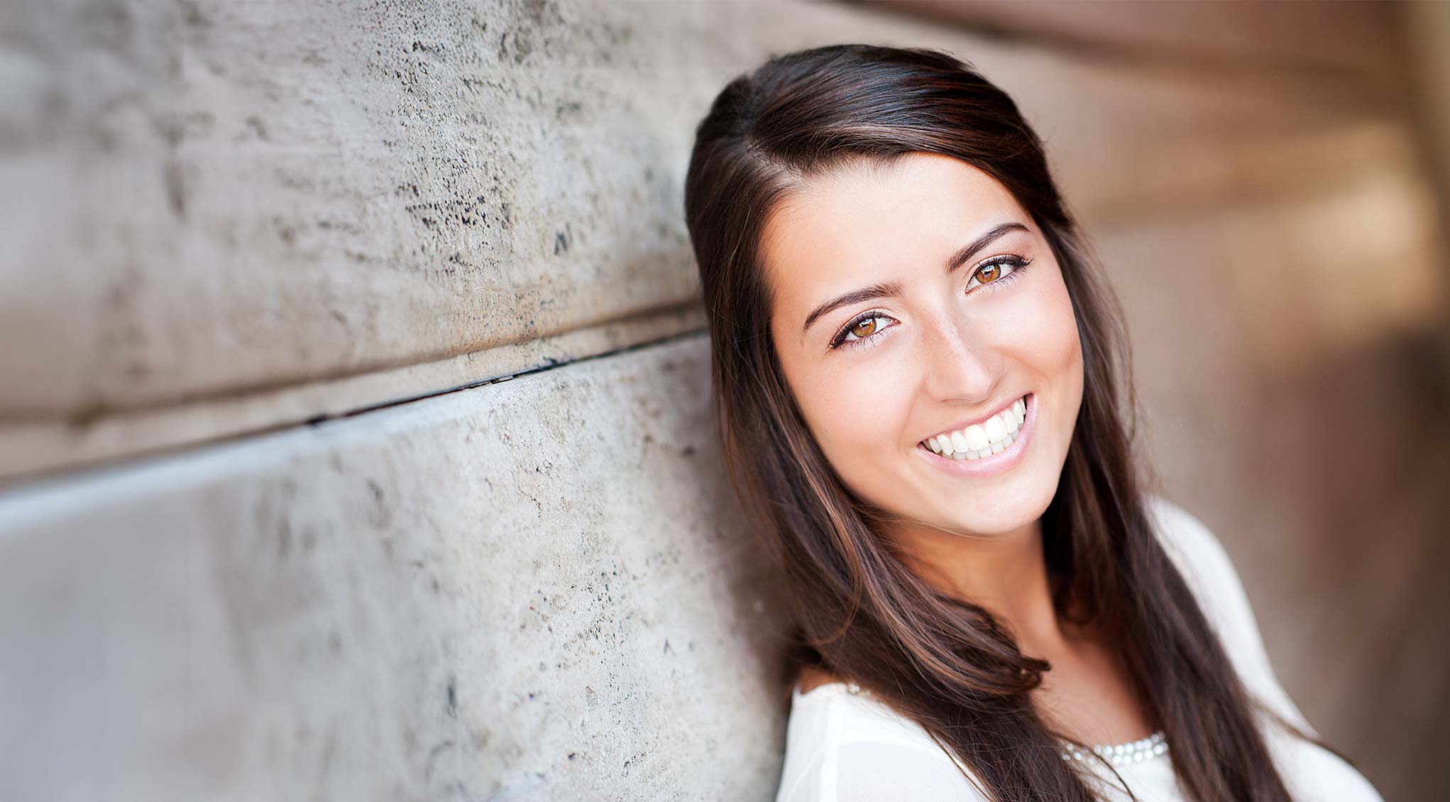 A young woman who is a patient from our Eagle River Orthodontic office, smiles after having braces.